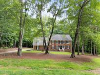 Traditional two-story brick home with a symmetrical facade and a welcoming front porch surrounded by mature trees at 221 Jansmith Ln, Raleigh, NC 27615