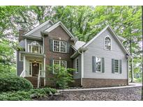 Charming two-story home with a brick and gray siding exterior, surrounded by lush greenery and trees at 2325 Old Oak Pl, Hillsborough, NC 27278