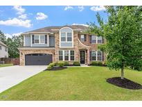 Beautiful two story home with a well manicured lawn, stone and brick exterior, and gray two car garage at 2333 Lantern Walk Ln, Wake Forest, NC 27587