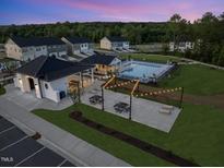 Community clubhouse and pool area with seating, string lights, and landscaping at dusk at 252 Meadowbark Bnd # 46, Garner, NC 27529