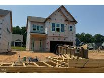 New home construction shows covered in weather proofing with garage and front door, dumpsters, and building materials at 252 Meadowbark Bnd # 46, Garner, NC 27529