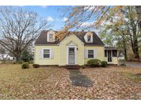 Charming yellow cottage-style home with dormer windows and a landscaped front yard in a beautiful autumnal setting at 345 Henderson St, Oxford, NC 27565
