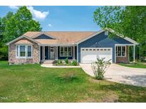 Charming single-story home featuring stone accents, a two-car garage, and a well-manicured lawn at 390 Lake Magnolia Way, Smithfield, NC 27577