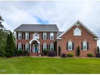 Stately brick home with manicured lawn, dark shutters, and a welcoming blue front door at 5009 Beckwyck Dr, Fuquay Varina, NC 27526