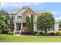 Charming home featuring a stone facade, manicured lawn, and inviting front porch at 5516 Colonial Oaks Dr, Apex, NC 27539
