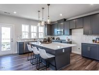 Modern kitchen boasts gray cabinetry, stainless steel appliances, and a large quartz island with pendant lighting at 809 Hyperion Aly, Wake Forest, NC 27587