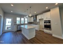 Modern kitchen features a large island with pendant lighting and stainless steel appliances at 809 Hyperion Aly, Wake Forest, NC 27587
