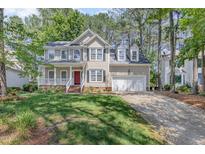 Traditional two-story home with a well-manicured lawn, red door, and white trim at 9308 Carisbrook Ct, Raleigh, NC 27615