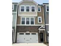 Inviting townhome with brick facade, white garage door, and neutral-toned siding at 10011 Secluded Gdn Dr # 169, Apex, NC 27523
