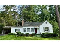 Charming single-story home featuring a brick chimney and a red front door surrounded by lush landscaping at 1609 Cypress Dr, Henderson, NC 27536