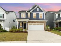 Charming two-story home featuring blue siding, stone accents, and a spacious two-car garage at 1725 Winter Jasmine Ln, Wake Forest, NC 27587