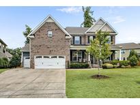 Beautiful two-story brick home with a manicured lawn and three-car garage on a sunny day at 2100 Della Ct, Apex, NC 27502