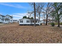 Charming single-story home featuring black shutters, white siding, and a cozy front porch at 2400 Dorety Pl, Raleigh, NC 27604