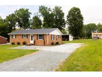 Charming brick home with gravel driveway, and well-maintained landscaping at 250 Patterson Dr, Roxboro, NC 27573