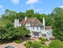 Stunning aerial view of an elegant white brick home surrounded by lush greenery and a charming brick patio at 3307 Devon Rd, Durham, NC 27707