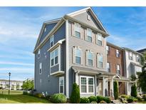 Charming gray townhome with manicured front yard and blue sky background at 5910 Giddings St, Raleigh, NC 27616