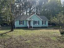Charming single-story home with a light-green exterior and black shutters, surrounded by a spacious yard at 803 Flat Rock Church Rd, Louisburg, NC 27549