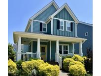 Charming two-story home with a welcoming front porch, yellow door, and manicured landscaping at 1448 Big Falls Dr, Wendell, NC 27591