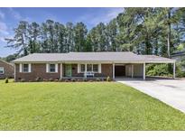 Charming brick home featuring a well-manicured lawn, covered parking, and a vibrant green door at 3009 Wellington Dr, Rocky Mount, NC 27803