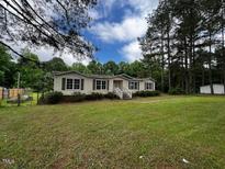 Quaint single-story home with green lawn, trees, and a white picket fence, perfect for Gathering living at 4040 Tyler Dr, Oxford, NC 27565