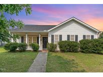 Charming single-story home featuring manicured landscaping and a welcoming front porch with classic black shutters at 5437 Advantis Dr, Raleigh, NC 27610
