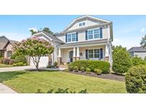Charming two-story home features a well-manicured lawn and a blooming tree, creating a welcoming curb appeal at 633 Copper Beech Ln, Wake Forest, NC 27587
