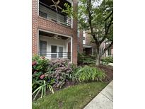 Brick condo exterior features colorful hydrangeas, lawn, sidewalk, porch, and black railing at 710 N Person St # 103, Raleigh, NC 27604