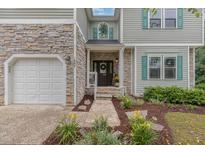 Inviting home featuring a stone facade, attached garage, and manicured landscaping at 1003 Burnt Hickory Ct, Apex, NC 27502