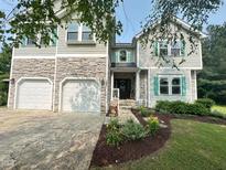 Charming home featuring a stone facade, two-car garage, manicured lawn and beautiful green shutters at 1003 Burnt Hickory Ct, Apex, NC 27502