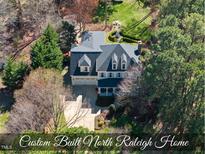 Stunning aerial view of the custom-built home featuring a manicured lawn, stone seating area, and mature landscaping at 1006 Henny Pl, Raleigh, NC 27614