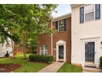 Charming brick townhome featuring a well-maintained lawn and mature landscaping at 10941 Pendragon Pl, Raleigh, NC 27614