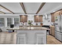 Bright kitchen featuring a large island with seating, stainless steel appliances, and wooden beams at 1118 Oakridge Duncan Rd, Fuquay Varina, NC 27526