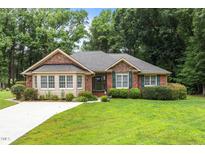 Charming brick home featuring a well-manicured lawn and beautiful green shutters at 143 Cedarwood Dr, Henderson, NC 27536