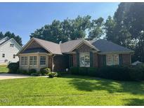 Charming brick home with well-maintained lawn and mature trees offering great curb appeal at 143 Cedarwood Dr, Henderson, NC 27536
