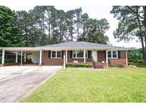 Charming brick home with mature trees and a well-maintained lawn, enhancing curb appeal at 205 N Augusta Ave, Benson, NC 27504