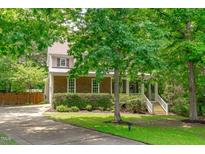 Charming home featuring a manicured lawn, mature trees, and a welcoming front porch with white railings and steps at 297 Curragh Cv, Fuquay Varina, NC 27526