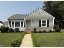 Charming single-story home featuring gray siding, black shutters, and a well-manicured front yard with a stone walkway at 306 W Canary St, Dunn, NC 28334