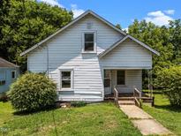 Charming exterior view of a quaint two-story home featuring a well-maintained lawn and mature trees at 312 W Front St, Oxford, NC 27565