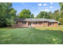 Charming single story brick home with manicured front lawn and a welcoming, covered front porch at 4964 Stafford Mill Rd, Liberty, NC 27298