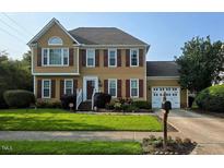 Charming two-story home with red shutters, a well-manicured lawn, and attached two-car garage at 5301 Peacenest Dr, Raleigh, NC 27610