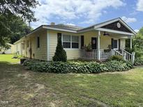 Charming yellow home with a welcoming front porch and well-maintained landscaping at 9439 Clayton Blvd, Clayton, NC 27520