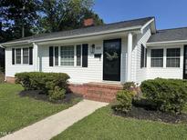 Charming single-story home featuring a classic black front door with a decorative wreath and a well-manicured lawn at 109 N Watauga Ave, Dunn, NC 28334