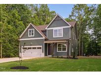 Charming two-story home featuring a garage, complemented by a well-manicured lawn and mature trees at 114 Crow Dr, Louisburg, NC 27549