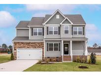 Charming two-story home showcasing stone accents, gray siding, and a welcoming front porch at 11640 International Dr, Middlesex, NC 27557