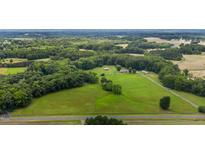Expansive aerial view of a property featuring lush greenery, a red barn, and a charming home at 1167 John D Winstead Rd, Roxboro, NC 27574