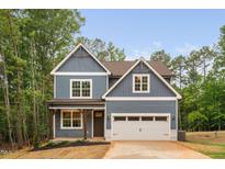 Charming two-story home featuring a blue exterior, a two-car garage and a well manicured front yard at 125 Oswego Dr, Louisburg, NC 27549