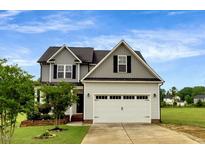 Charming home with a two-car garage, well-maintained lawn, and a mix of siding and roof shingles at 131 Hawick Ct, Zebulon, NC 27597