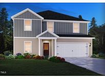 Charming two-story home featuring a white garage door, grey siding, and a manicured lawn with colorful flowers at 2254 Cherry Creek Rd, Haw River, NC 27258