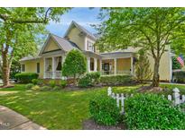 Charming yellow home with inviting front porch, lush landscaping, and a classic white picket fence at 4001 Falls River Ave, Raleigh, NC 27614