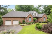 Traditional brick home featuring manicured landscaping, a two-car garage, and an American flag at 414 Bakewell Ct, Wake Forest, NC 27587